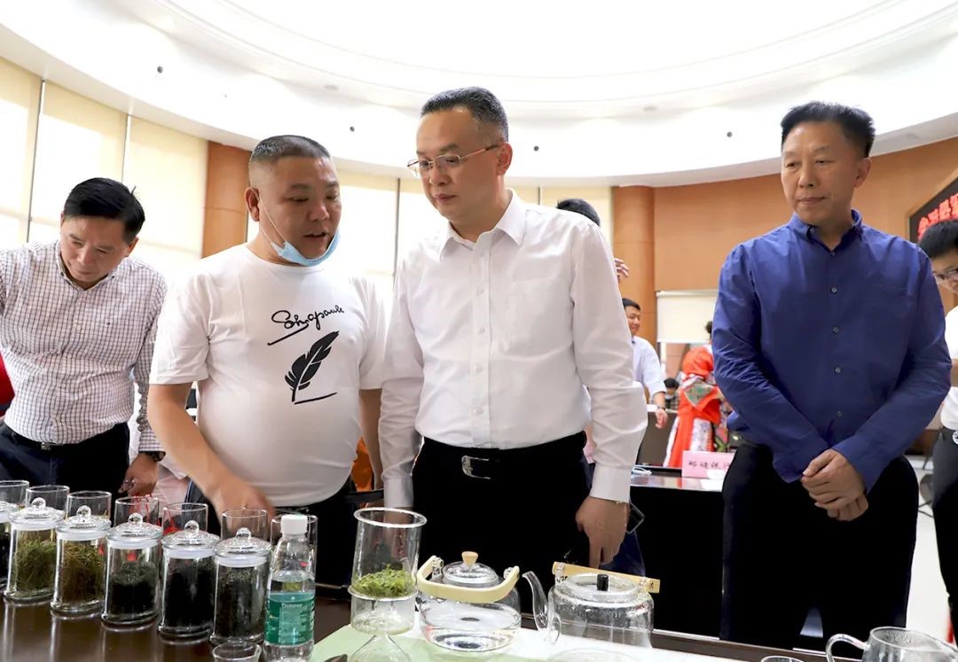 龙家界村村委会书记杨胜华(左二)向周振武(右二)介绍茶叶等农副产品